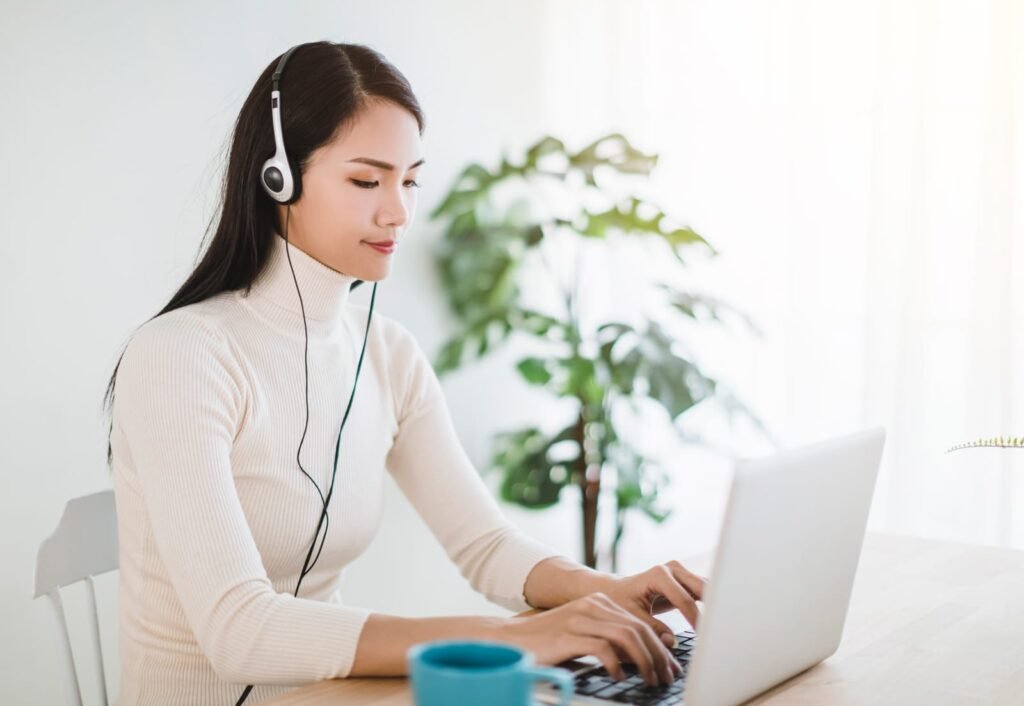 Young woman working on laptop and using video call in living room at home