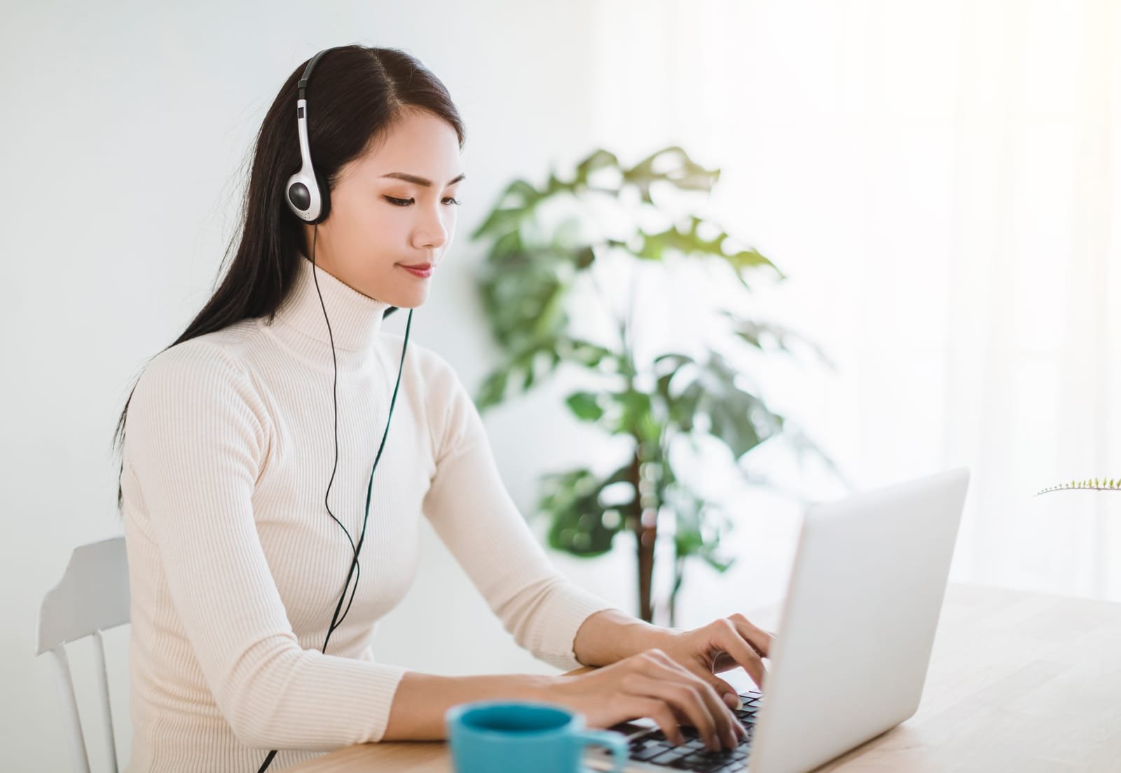 Young woman working on laptop and using video call in living room at home