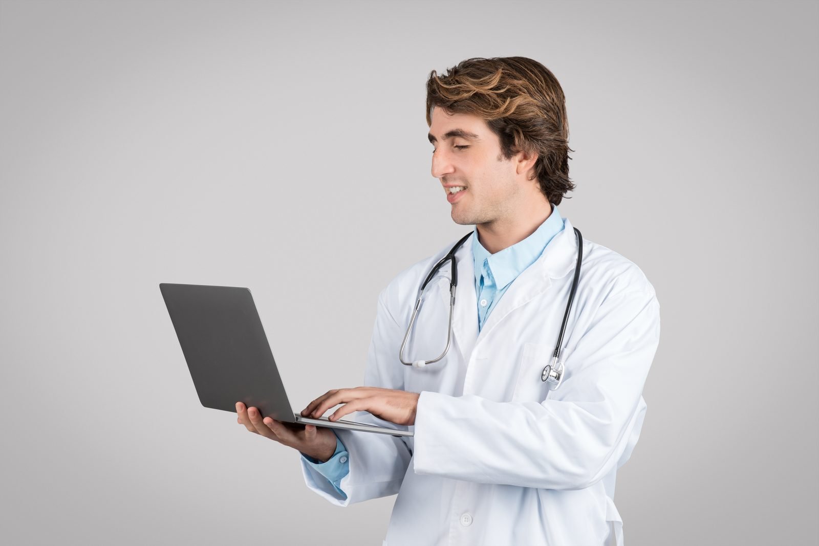 Male doctor typing on laptop gray background – online vet doctor