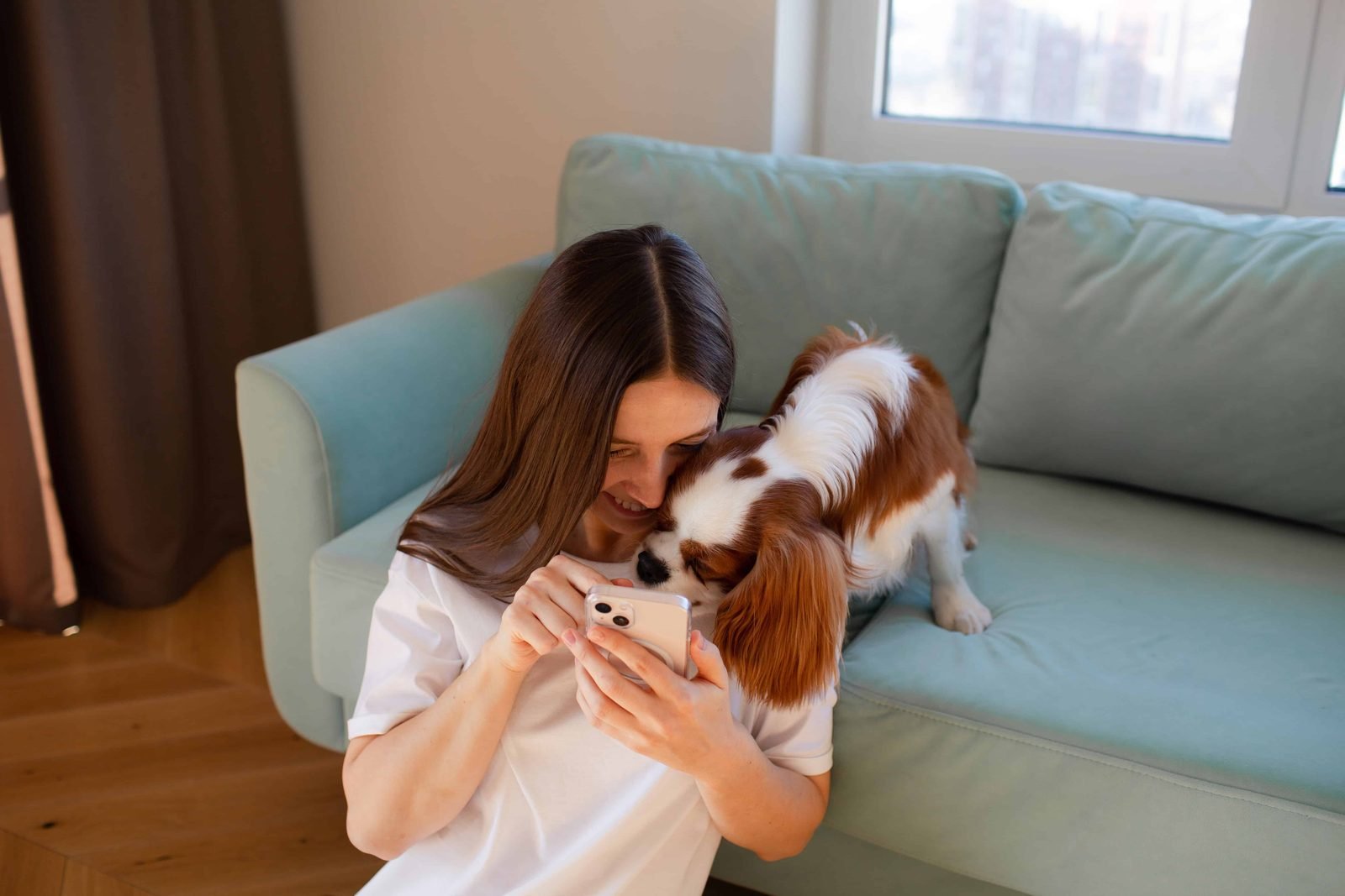 Woman sitting at home with her dog and a phone