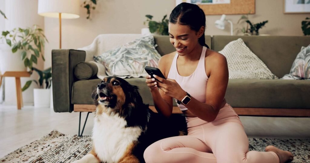 Woman at home with her dog, looking at a phone